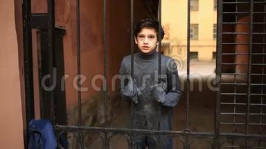 一个无家可归的少年透过铁栅栏看着摄像机