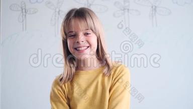 小女孩微笑着看着相机，呆在家里的白板前。