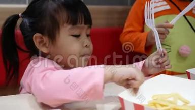亚洲同胞小女孩喜欢吃炸鸡，薯条和花蜜在服务商店与她的家人。 <strong>肯德基</strong>是一家