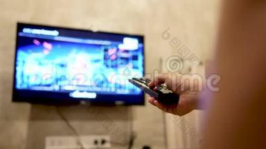 亚洲年轻女子在房间里看电视，手里拿着遥控器调节音量或<strong>更换</strong>电视频道。 在l中放松