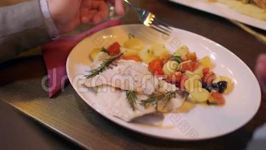在餐馆里，一个人在桌上端着配菜，吃着头的鱼片