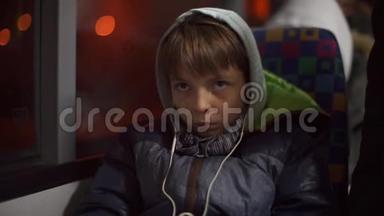 一个戴着耳机的青少年坐在<strong>公共交通</strong>巴士上的乘客座位上。