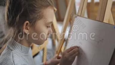 画画学校的女孩学画静物.. 女孩用铅笔在一张纸上画素描的特写