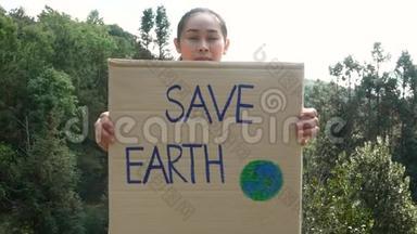 这位年轻女子手持`拯救地球`海报，展示了一个抗议森林中塑料污染的标志。 的概念