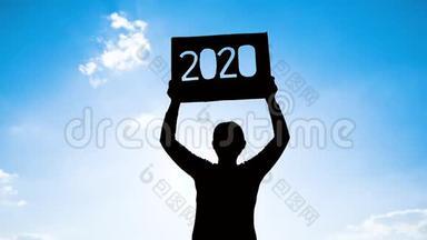 女人拿着回收纸板<strong>的</strong>剪影，用2020年<strong>的</strong>文字在蓝天背景和阳光下通过文本。 概念