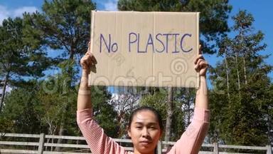 那个年轻女子拿着`没有塑料`海报，上面有一个标志，抗议森林中的塑料污染。 Worl的概念