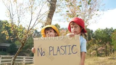 两个小女孩兄弟<strong>姐妹</strong>拿着`没有塑料`<strong>海报</strong>，上面有一个标志，抗议森林中的塑料污染。 这就是