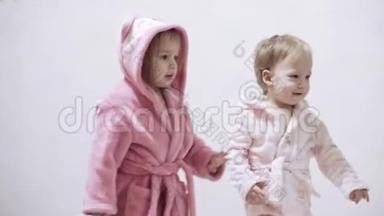 两个孩子穿着<strong>浴袍</strong>在一个<strong>白色</strong>背景和湿发后洗澡。 在<strong>白色</strong>床上洗澡后的男孩和女孩