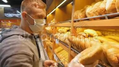 带医用口罩的年轻人在超市里选择了一条新鲜的面包。 在生产部挑选食物的人