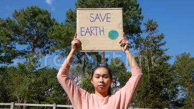 这位年轻女子举着`拯救地球`的<strong>海报</strong>，<strong>展</strong>示了一个抗议森林中塑料污染的标志。 的概念