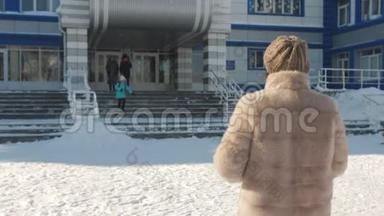 妈妈<strong>冬天</strong>穿着一件皮<strong>大衣</strong>，在学校门口下课后遇到一个小女儿。