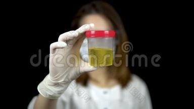 尿液在一个<strong>检测</strong>银行特写。 女<strong>医生</strong>拿着一罐尿到黑色背景上的相机上。