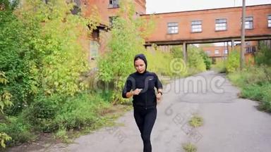 穿着黑色<strong>运动服</strong>的<strong>女孩</strong>穿过一家废弃工厂的领地。