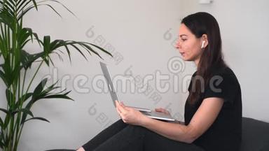 年轻女子坐在家里，手提电脑和无线耳机，并有<strong>视频</strong>聊天。 在线<strong>教育</strong>