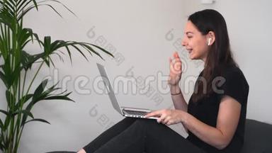 年轻女子坐在家里，手提电脑和无线耳机，并有<strong>视频</strong>聊天。 在线<strong>教育</strong>