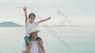 快乐的亚洲家庭，与父子两人在海滩上挽着飞机，玩得开心快乐