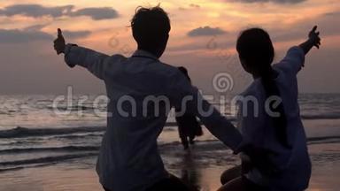 亚洲家庭幸福的<strong>剪影</strong>，在度假时，一起在海滩上拥抱和<strong>亲吻</strong>女儿的脸颊