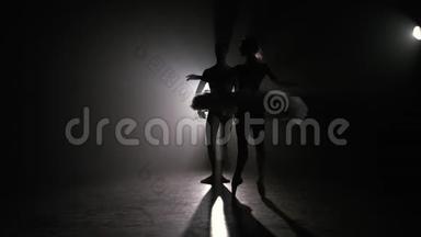 专业芭蕾舞情侣在聚光灯下跳舞，在大舞台上抽烟。