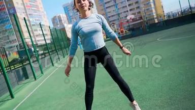 那个女孩在街道上的一个围栏地区参加体育活动。 街头健身操.. <strong>蹲着</strong>跳起来。 这就是