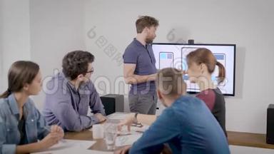 在办公室报到.. 一个人以自己的方式为同事做演讲。 商业幻灯片显示在电视上。