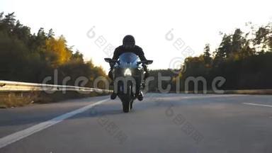 摩托车手在乡村公路上驾驶摩托车. 戴着头盔的年轻人骑着高速公路上的现代摩托车