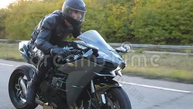 在高速公路上骑着现代摩托车的戴着头盔的年轻人。 骑摩托车的摩托车