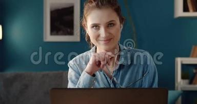 带着笔记本电脑坐在办公桌前微笑的女人的肖像