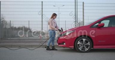 女孩在车站给电动车充电.. 女士正在为电动汽车充电汽车电池。 电气