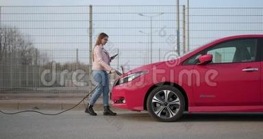 电动汽车中的女孩插头充电器连接器。 揭示电动插座充电新的，高效的汽车在街上。