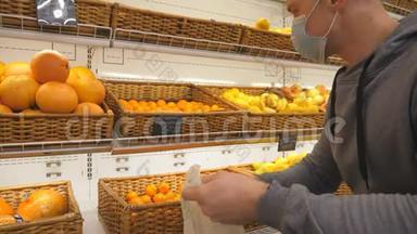 带医疗面罩的人在商店里挑选曼达林。 男人在超市里选择水果。 购买农产品