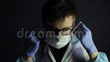 一位年轻的白种人医生戴着医用防护面罩。 竖起大拇指。 暗黑背景。 医用手套。