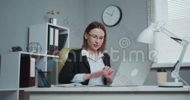 快乐的女人用笔记本电脑做网上银行，微笑着用笔记本电脑上的在线应用支付账单