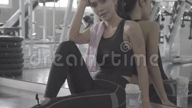 美丽的年轻亚洲女人在健身房锻炼后疲惫疲惫，亚洲女孩有汗水和呼吸休息