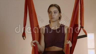 坐在瑜伽室吊床上的女人。吊床上练习飞行瑜伽的女孩