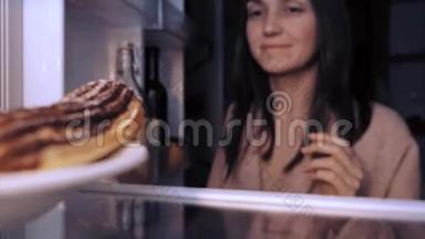 女人正在<strong>打开</strong>一个<strong>冰箱</strong>，拿着一个麦片，高兴地吃着它