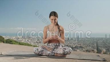 在<strong>城市</strong>里看智能手机<strong>屏幕</strong>的女人。 坐在垫子上摆着莲花姿势的女士