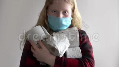 因冠状病毒流行而被隔离。 戴面具的女孩，在灰色背景上摆着一卷<strong>卫生纸</strong>。