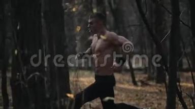 年轻的肌肉运动员在森林里<strong>奔跑</strong>。 在树之间<strong>奔跑</strong>。 慢动作