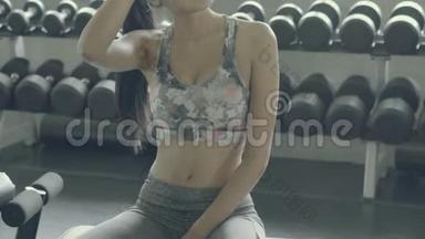 美丽的年轻亚洲女人在<strong>健身房</strong>锻炼后疲惫而疲惫，亚洲女孩有汗水和擦拭<strong>休息休息</strong>时间