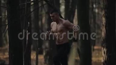 年轻的肌肉运动员在森林里奔跑。 在树之间奔跑。