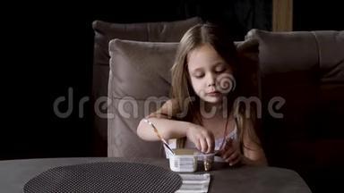 坐在桌子旁吃酸奶的小女孩。 儿童食品