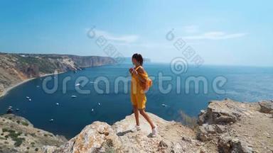 黝黑的<strong>旅人</strong>女人站在悬崖边，穿着明亮的黄色连衣裙在风中飘扬。