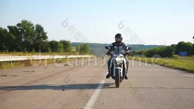 戴头盔的人骑着高速公路上的快速摩托车。 摩托车手在风景优美的自然景观中骑摩托车