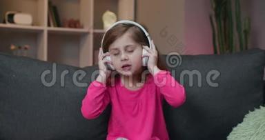 小女孩听无线耳机音乐。 有趣的小女孩跳舞，<strong>唱歌</strong>和移动到节奏。 <strong>孩子</strong>
