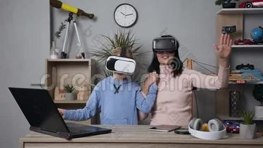 漂亮的黑发年轻女子与她的少女微笑的儿子玩电子游戏，使用保护虚拟3D眼镜