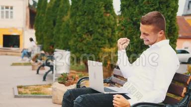 成功的红发男子，穿着<strong>商业风</strong>格，坐在公园的户外，在笔记本电脑上打字。