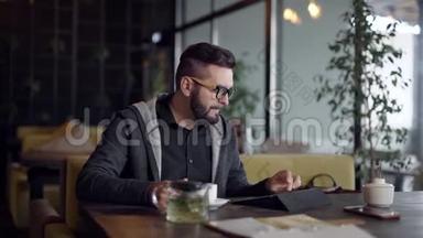 独自一人的年轻人白天独自在咖啡馆里休息，用平板电脑，喝着杯子里的热茶