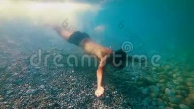 一个运动的青少年潜<strong>入水</strong>下，在清澈的蓝色热带<strong>水</strong>中沿着海底游泳，慢动作，Gopro7黑色。