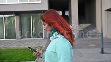 一个穿着薄荷运动衫的红发美女在街上走来走去，在电话里聊天。 快乐女孩自拍