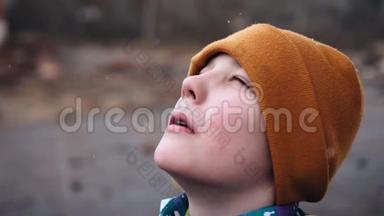 一个快乐的男孩站在那里，抬头仰望天空，捕捉雪花